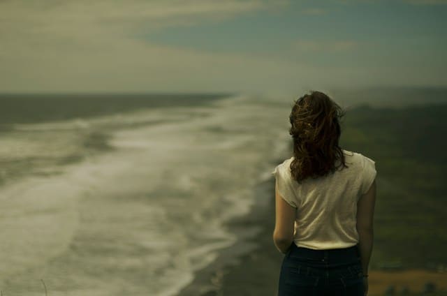 femme marchant au bord de l'eau, regardant les vagues