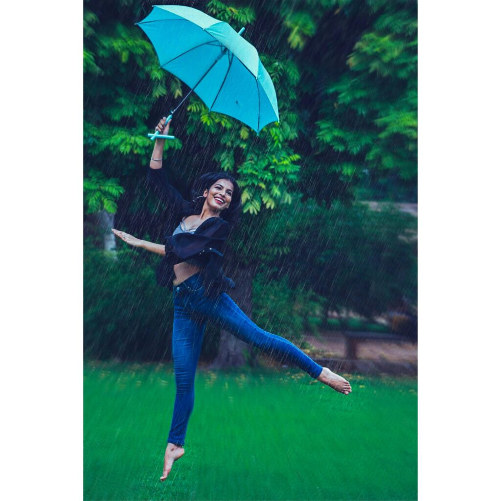 femme dansant sous la pluie, tenant un parapluie ouvert de couleur bleu