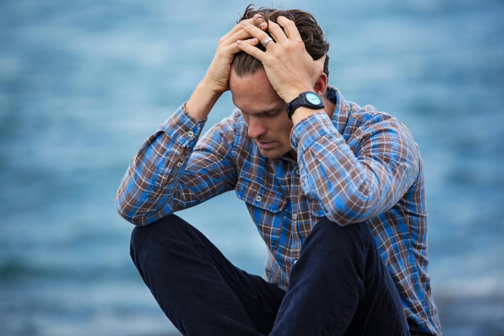 homme portant une chemise bleu, posant ses mains à la tête