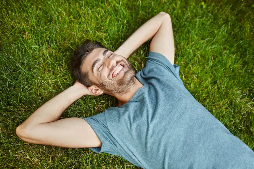 Emotions Positives homme couché sur l'herbe souriant se détendre à l'extérieur